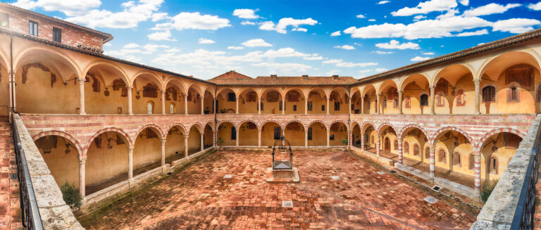 Panoramic view with the scenic courtyard in the friary of the Basilica of Saint Francis, Assisi, Italy. UNESCO World Heritage Site since 2000